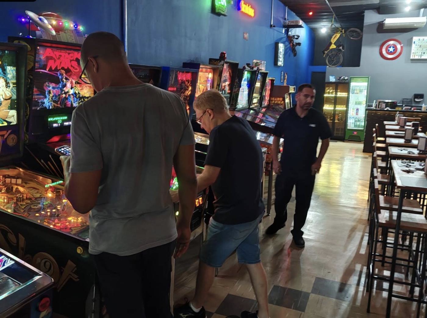 Vista geral do salão da Base Experience, com fileira de pinballs e decoração retrô