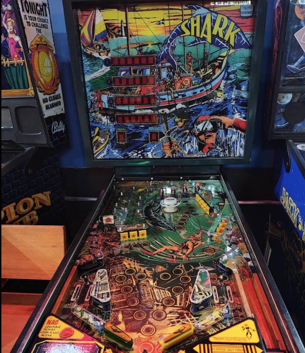 Pessoas jogando pinball na Base Experience à noite